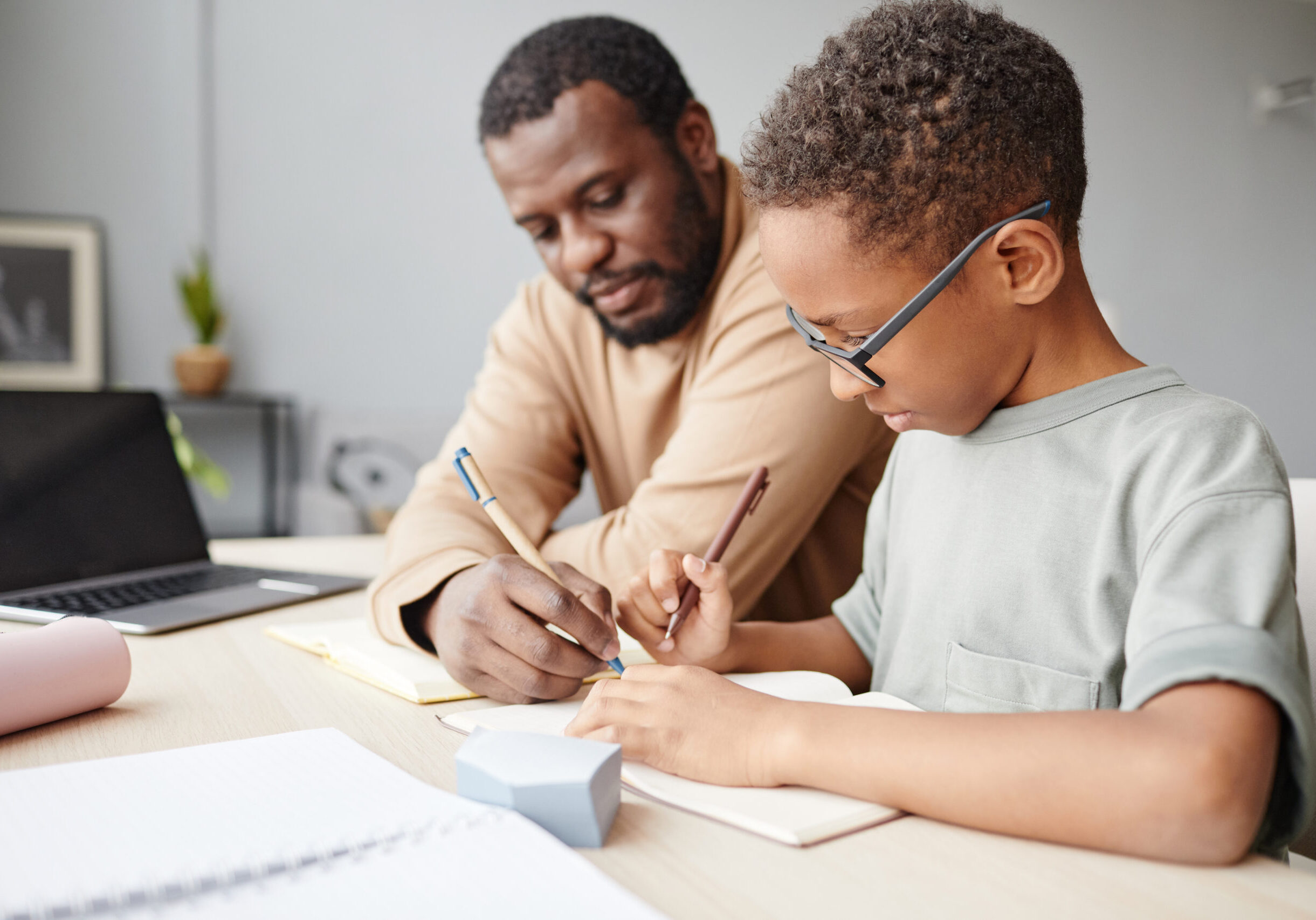 black child studying at home with father