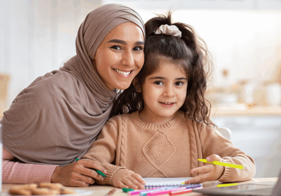 Mother in hijab smiling with daughter.