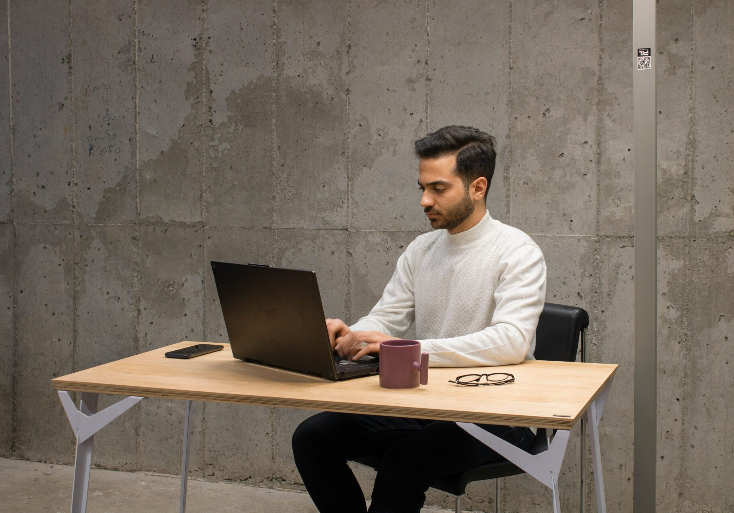 South Asian man studying at desk with laptop.